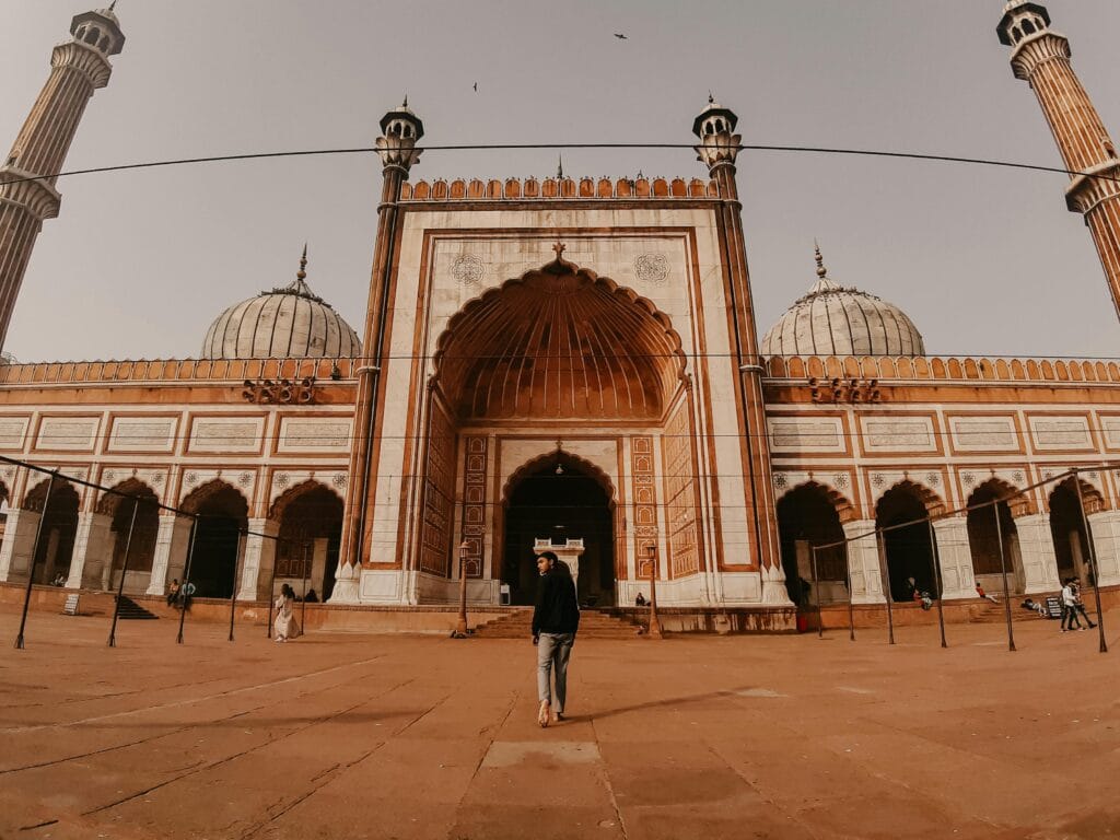 pexels-photo-5562362-5562362 Low angle view of Jama Masjid with minarets at sunset, a man walking in the foreground.